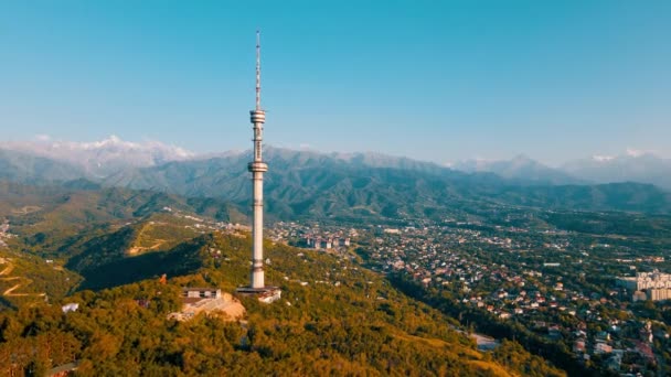 空中ドローンは カザフスタンの雪山に対するコクトーベ丘のシンボル高いテレビ塔と公園のショットを明らかにします — ストック動画