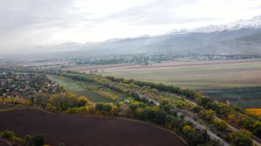 Sonbahar zamanı, Kazakistan 'ın Almaty şehrinde, dağların tepesinde, taşımacılık ve sarı ağaç ormanıyla yol kenarındaki arazinin hava aracı manzarası.