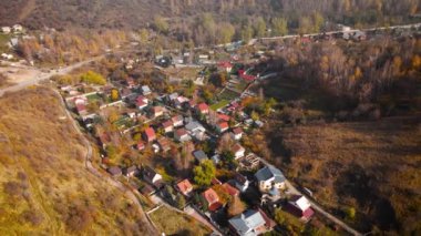 Sonbahar zamanı Kazakistan 'ın Almaty şehrinde, dağlarda sarı ağaç ormanı yakınlarındaki yol ve köy hortumlarının hava aracı manzarası