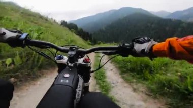 Dağ bisikletçisi Green Mountain Ormanı 'nda elektrikli motosiklet sürüyor. Parmaklıkların arkasındaki POV Bisikletçinin görünümünde.