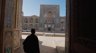 Sırt çantalı bir turist Özbekistan 'ın Buhara kentindeki Medrese Kapısı' nda yürüyüş yapıyor.