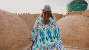 Özbekistan 'ın Itchan Kala antik kenti Khiva' daki şehir duvarında mavi süslemeli ve şapkalı genç kadın portresi.