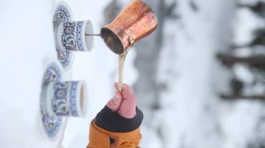 Man 'in dikey videosu dağlardaki Copper Cezve' den kahve hazırlıyor. Ibrik 'den Türk bardağına kadar ağır çekimde etnik süslemeli içecek dökün