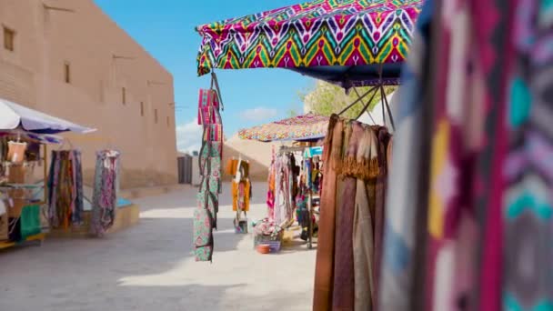 在乌兹别克斯坦基瓦和中亚 街头市场上流动缓慢的带有传统装饰的五彩缤纷的民族布 包和围巾 — 图库视频影像