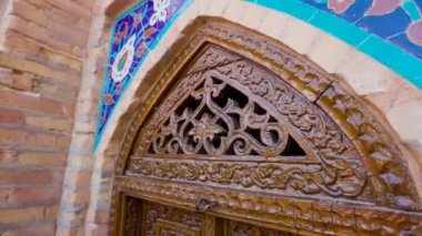Turist kadın, Özbekistan 'ın Semerkand kentindeki mavi gökyüzüne karşı Gur Emir Anıtmezarı' nda geleneksel oymacılığa elle dokunuyor