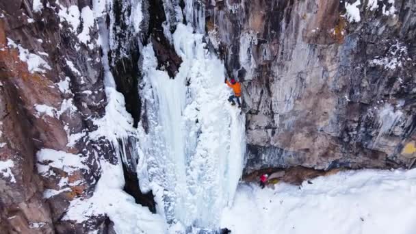 カザフスタンのアルマトイ市近くの山に大きな凍った滝を登るアスリート氷の空中ドローンビュー — ストック動画