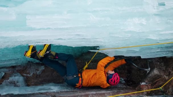 Вертикальное Видео Спортсмена Оранжевой Куртке Топоре Карабкающегося Льду Большого Замерзшего — стоковое видео