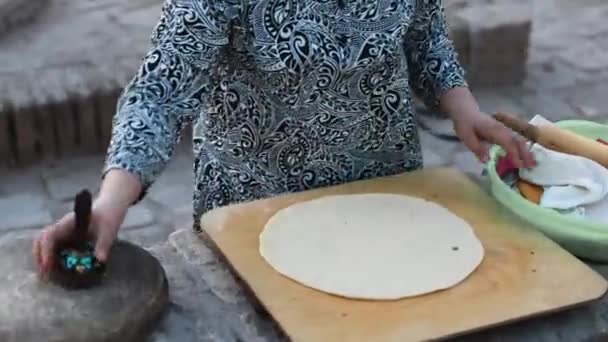 キヴァ オスベキスタン セプトラー23 2023 チキと呼ばれる特別なデバイスでフラットブレッドで伝統的なドレス描画パターンの女性 タンドールオーブンでパンを焼く家族と子供 — ストック動画
