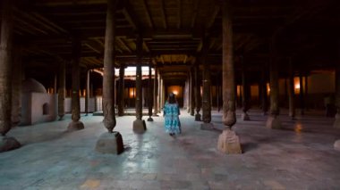 Juma Camii, Khiva, Özbekistan 'da oymalarla süslenmiş ahşap sütunlar içindeki etnik kadın..