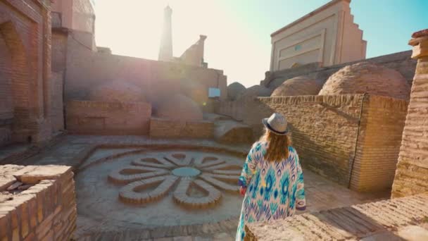 장식과 모자와 드레스에 여자는 마드라사 배경에 도시의 광장에서 우즈베키스탄의 — 비디오