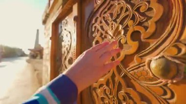 Mavi süslemeli genç kadın Özbekistan 'ın Itchan Kala antik kenti Khiva' nın eski ahşap kapısına dokundu.