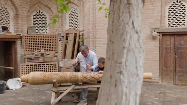 齐贝肯 2023年9月24日 父亲和他的儿子在小作坊用铁锤将装饰品刻在木头上 文件编辑 — 图库视频影像