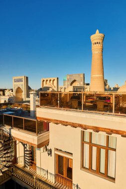 Roof top restaurant with topchan table bed in Bukhara near Kalyan Minaret  and madrasah in Uzbekistan clipart