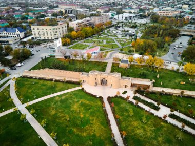 Aerial drone view of caravan sarai old culture and old fortress gate in the center of city Turkestan at sunset in South Kazakhstan clipart