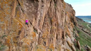 Pembe tişörtlü bir erkek sporcunun Güney Kazakistan 'daki Ili nehrindeki yüksek kayaya tırmanışı.