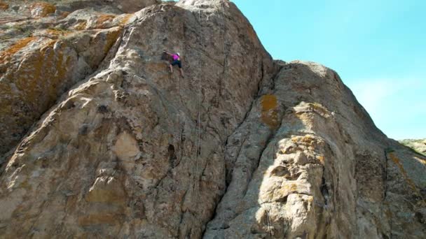 在哈萨克斯坦南部伊利河上 穿着粉色运动衫的男子运动员爬上岩石的空中照片 — 图库视频影像