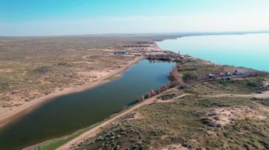 Gün doğumunda mavi deniz kenarında deniz feneri ve köy hortumlarının insansız hava aracı görüntüleri. Doğa manzarası arka planı.