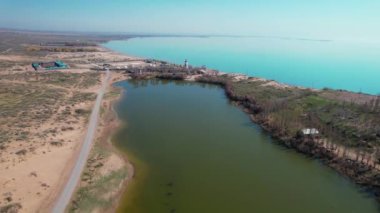 Gün doğumunda mavi deniz kenarında deniz feneri ve köy hortumlarının insansız hava aracı görüntüleri. Doğa manzarası arka planı.