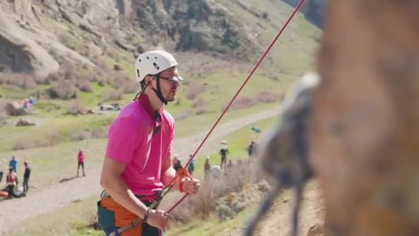 Homem Atleta Camisola Rosa Com Corda Superior Enquanto Trepa Rocha — Vídeo de Stock