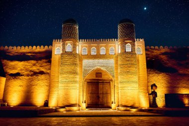 Özbekistan 'ın Khiva kentindeki Itchan Kala şehrinde yıldızlarla gece gökyüzüne karşı aydınlatma ile eski Kalta Minor minaresinin tarihi mimarisi. 