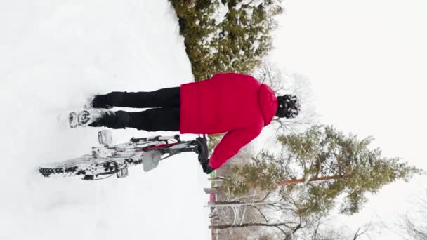 Kırmızı Ceketli Bir Adamın Karlı Parkta Bisikletiyle Yürüdüğü Dikey Bir Stok Video