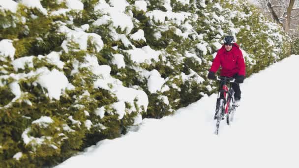 穿着红色夹克的男人骑着他的自行车在雪地公园里 哈萨克斯坦阿拉木图市冬季城市自行车 图库视频