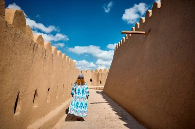 Özbekistan 'ın Itchan Kala antik kenti Khiva' da mavi süslemeli genç bayan şehir duvarında yürüyor.