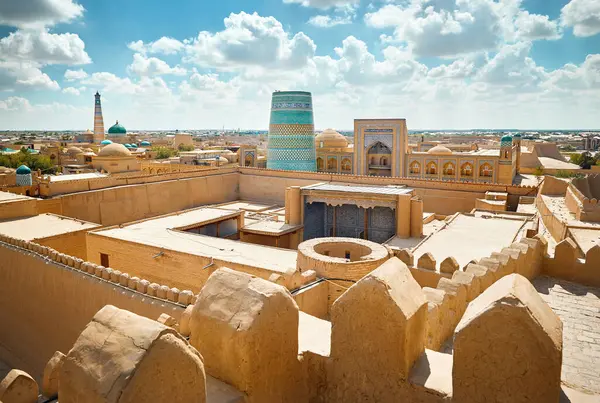 ウズベキスタンのキヴァの古代都市壁の要塞の屋根からカルタ ミナーレとアブドゥラ カーンのマドラスの夕日の景色 ストック画像