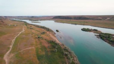 Ili nehri yakınlarındaki çadır ve Kazakistan 'daki mavi bulutlu gökyüzünde bahar bozkırlarının insansız hava görüntüsü.