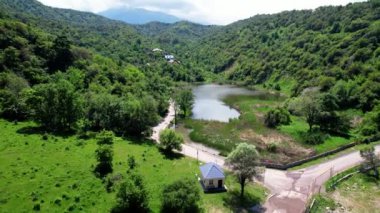 Sarı ceketli bisikletçi güneşli bir günde küçük göl kenarında kırsal yolda at sürüyor. Bisiklet turizmi kavramı.