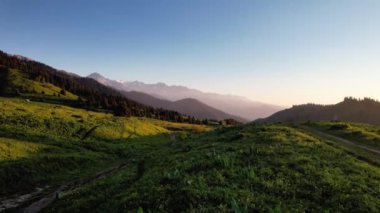 Dağ karlı zirvesinin güzel hava aracı manzarası ve Almaty, Kazakistan 'da günbatımı gökyüzünde yeşil ladin ormanı manzarası.