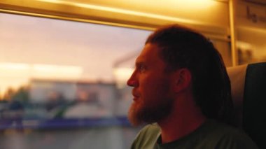 Korkunç kilidi olan genç sakallı bir adam gün batımında pencereden dışarı bakar. Taşkent 'ten Semerkand' a Talgo treni.