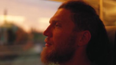 Korkunç kilidi olan genç sakallı bir adam gün batımında pencereden dışarı bakar. Taşkent 'ten Semerkand' a Talgo treni.