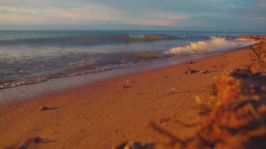 Gün batımında Issyk-kul Gölü 'nde küçük dalgalar olan boş kumlu bir sahil. Yazın Kırgızistan 'daki Kaji Sai köyü.