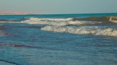 Gün batımında Issyk-kul Gölü 'nde küçük dalgalar olan boş kumlu bir sahil. Yazın Kırgızistan 'daki Kaji Sai köyü.