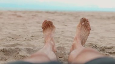 Issyk-kul Gölü 'nde kumlu kumsalda dinlenen bir adam bacaklarının üzerinde dalgalanır. Kırgızistan 'da yaz zamanı Tosor köyü.