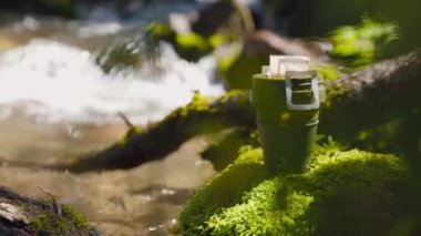 Yeşil bardakta kahve poşeti. Yaz ormanlarında, dağ nehrinin yakınındaki kayalıklarda sıcak suyla demlenen içeceğin işlemleri..