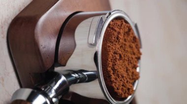 El baristasının el yapımı espresso yaparken çekilmiş dikey bir video. El yapımı kahve, kahve makinesiyle öğütülmüş.