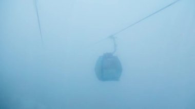 Kazakistan, Almatı 'daki Shymbulak dağ beldesinde kışın mavi sisli dağlarda teleferik.