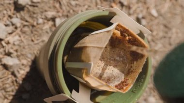 Yeşil bardakta kahve poşeti. Dağ gölünün yakınındaki kayanın termosundan gelen sıcak suyla demlenen içecek.