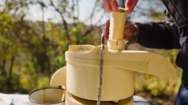 Erkek elleri bahçesindeki masada meyve sıkacağının içine elma koyar. Doğal elma suyu yapmak için yakın çekim..