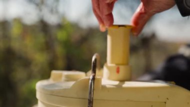 Erkek elleri bahçesindeki masada meyve sıkacağının içine elma koyar. Doğal elma suyu yapmak için yakın çekim..