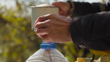 Erkek elleri boş şişeyi bahçesinde taze elma suyuyla dolduruyor. Eski meyve sıkacağının doğal elma suyunu yakın plan çekimleri..