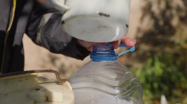 Erkek elleri boş şişeyi bahçesinde taze elma suyuyla dolduruyor. Eski meyve sıkacağının doğal elma suyunu yakın plan çekimleri..