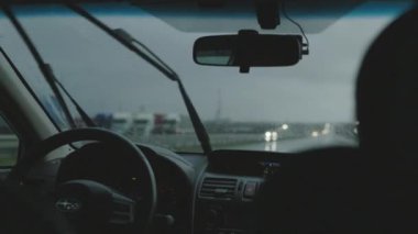 Otobanda çalışan sileceklerle yağmur fırtınasının içinden araba geçiyor. Uzak mesafeler kat et ve yağmur arabasının önüne düş. Direksiyonlu şoför silueti.