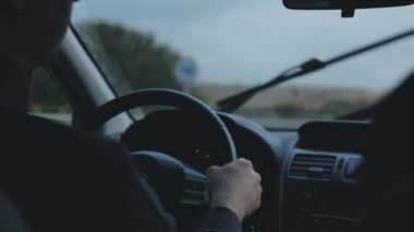 Otobanda çalışan sileceklerle yağmur fırtınasının içinden araba geçiyor. Uzak mesafeler kat et ve yağmur arabasının önüne düş. Direksiyonlu şoför silueti.