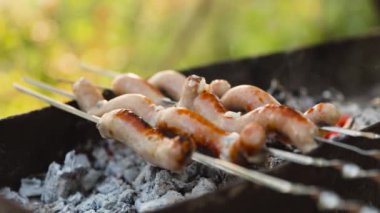 Barbeküdeki sosisler piknik bahçesinde duman ve alevlerle kaplıdır.