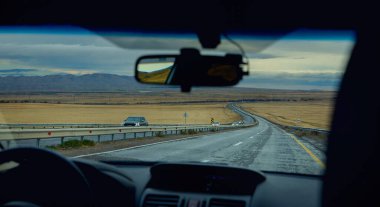 Yağmur fırtınasında kamyonlarla dağ yolunda giden arabanın ön camına bakın. Uzaklardan gel, direksiyon silueti olan şoför.