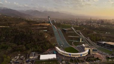 Gün batımında kayak kompleksi Sunkar 'ın Almaty, Kazakistan' da turuncu gökyüzü ve kar dağlarının insansız hava aracı görüntüleri.