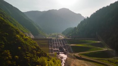 Almaty, Kazakistan 'da gün batımında dağlardaki büyük nehir barajının hava görüntüsü.